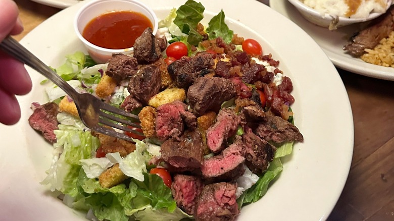 Texas Roadhouse salad with steak and dressing on the side