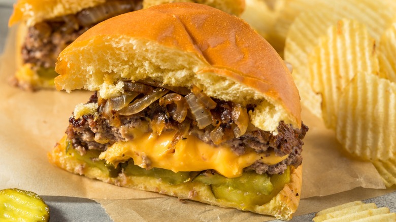 A halved cheeseburger with chips