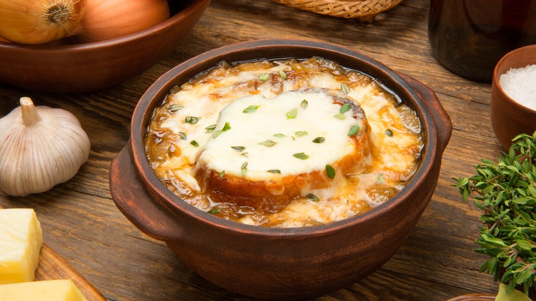 French onion soup in wooden bowl surrounded by ingredients