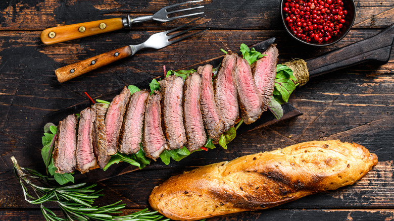 Sliced steak with baguette, arugula, and peppercorns