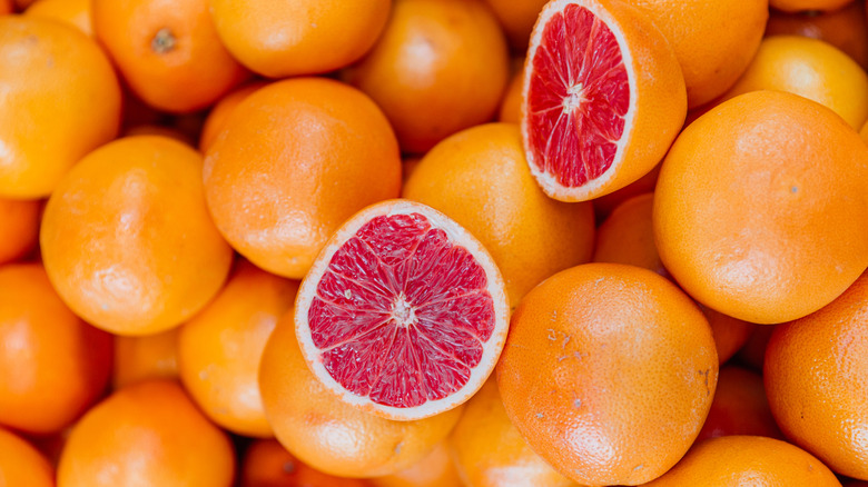 A pile of fresh grapefruits with one sliced in half