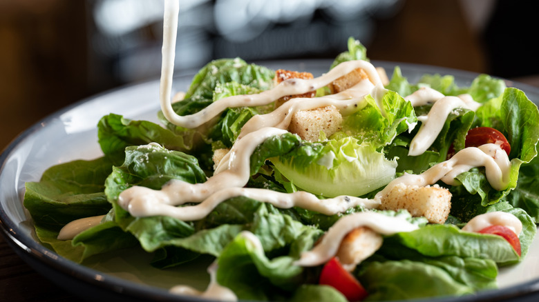 pouring dressing on a salad