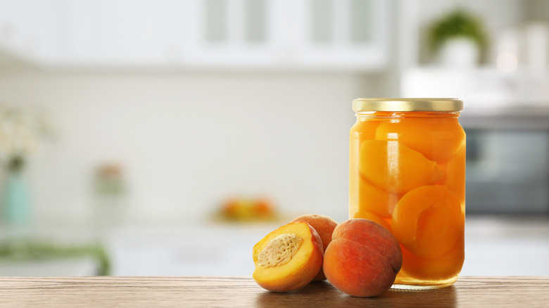 pickled peaches in jar next to raw peaches