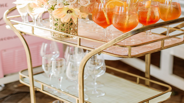 Gold bar cart with pre-made drinks on top shelf