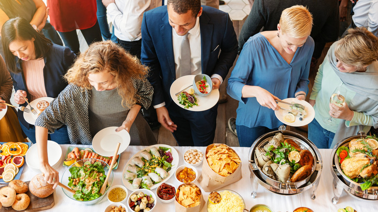 People taking dishes from a buffet