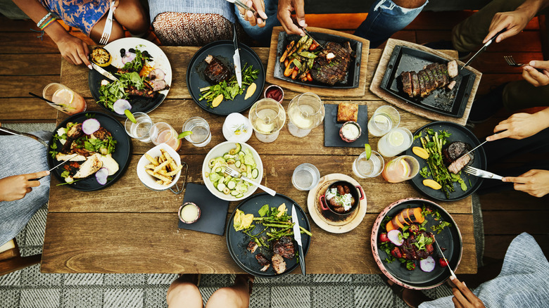 Top-down view of table of people eating with many plates and drinks in front of them