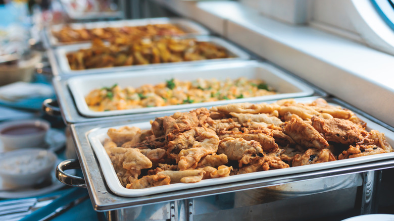 Buffet dish containing fried chicken with other dishes blurred in the background