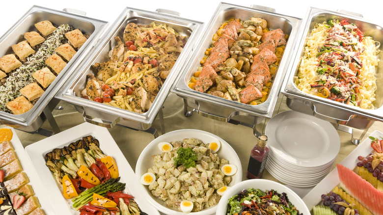 Buffet with chafing dishes in the back holding hot food items, trays up front holding cold items