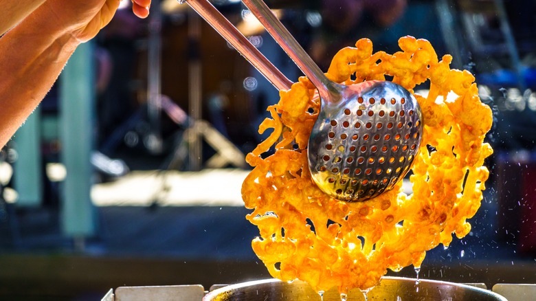 Funnel cake being removed from cooking oil