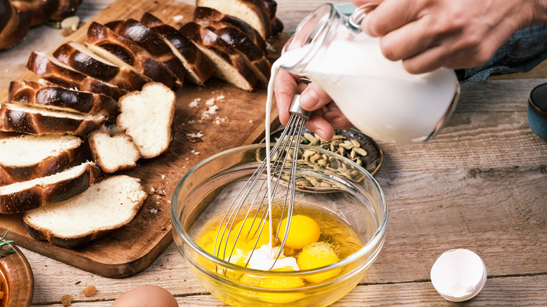 Hand pouring milk into egg with other ingredients