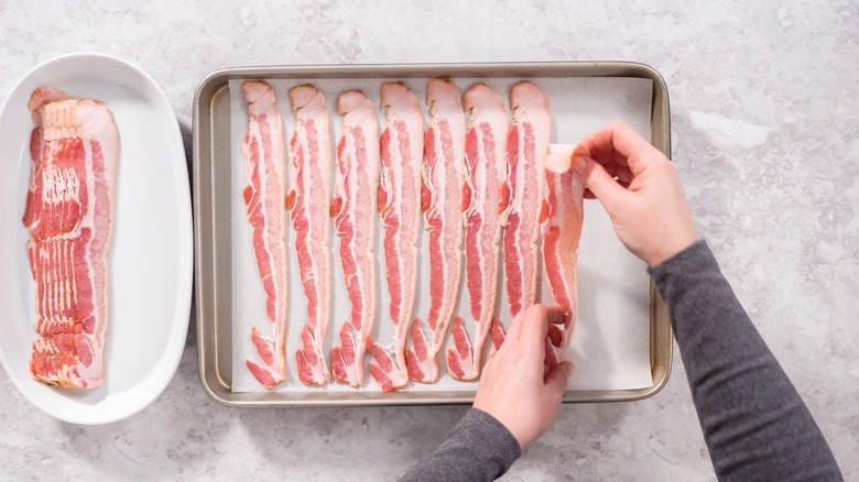 laying bacon onto a sheet pan