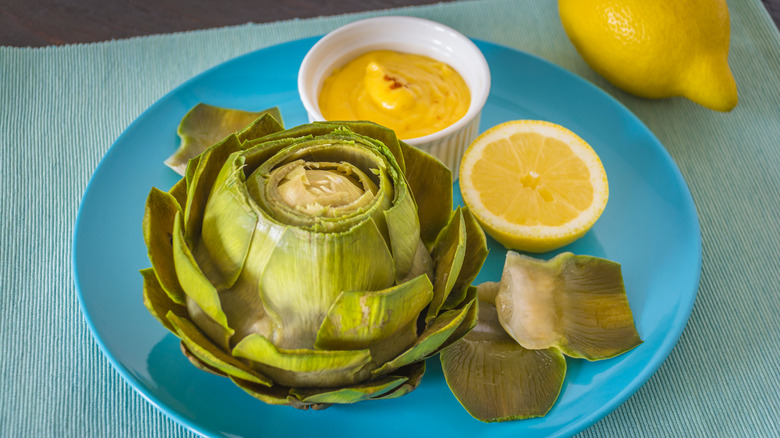 A steamed artichoke with lemon and Hollandaise sauce