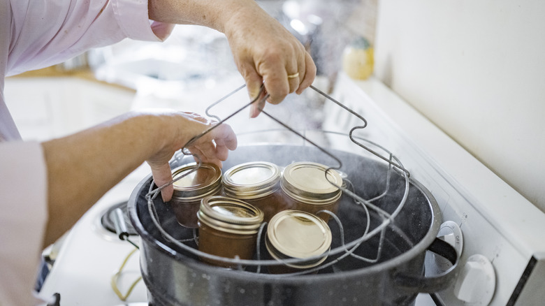 hands lifting cans out of canner