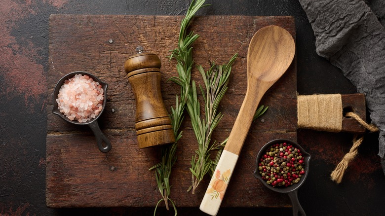 Pepper grinder and peppercorns on cutting board