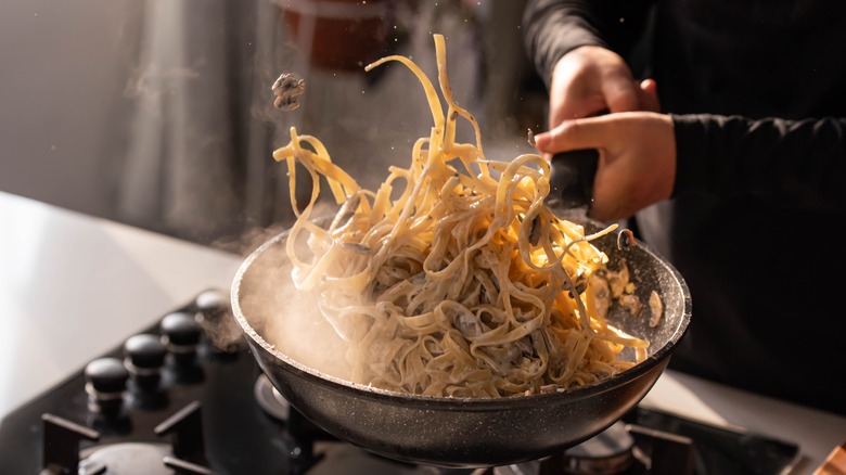 chef tossing pasta in pan