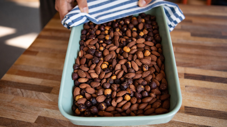 Someone holds out a tray of roasted almonds and hazelnuts