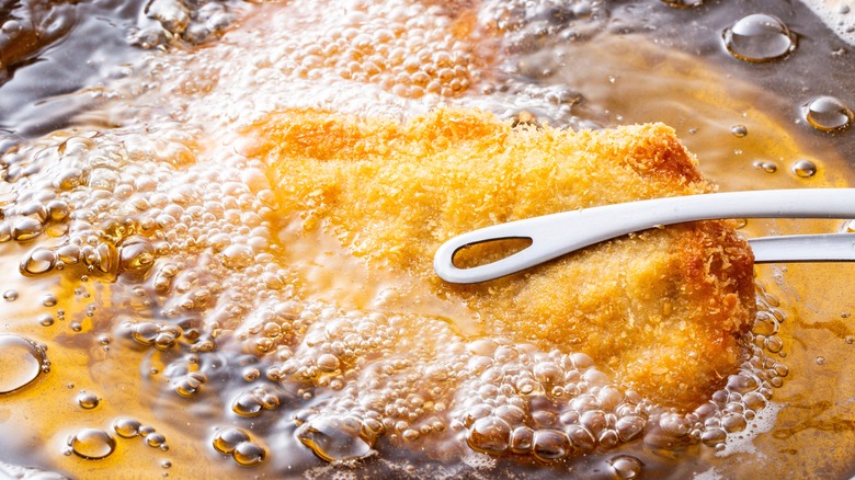 Close-up of a pork cutlet cooking in the fryer