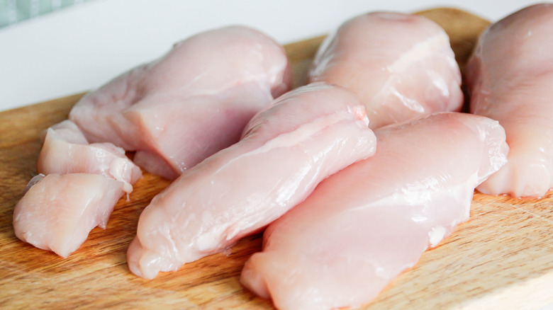 Raw chicken breasts resting on cutting board