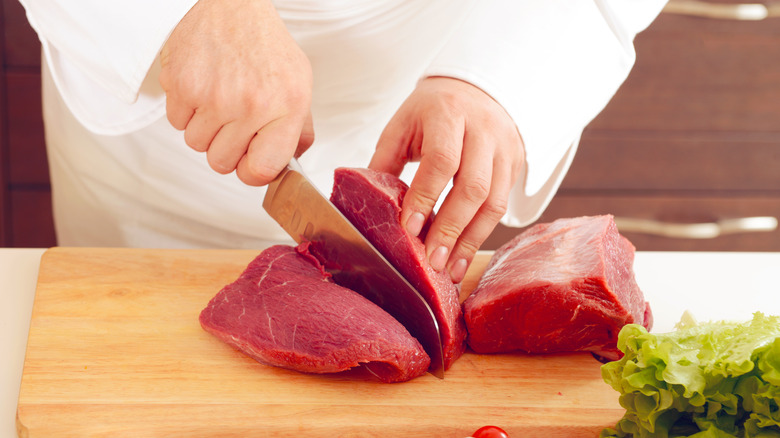 Chef cutting meat on board