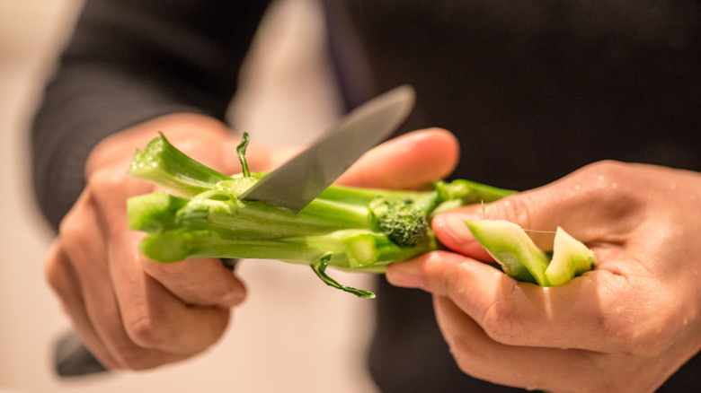 hands slicing a broccoli stalk