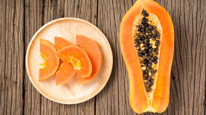 Halved and sliced papaya on wood