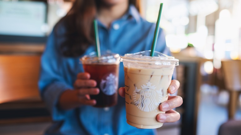 person holding out a Starbucks iced coffee and an iced latte