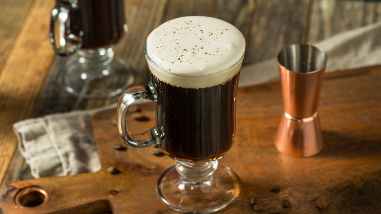 an irish coffee on a wooden board with a cocktail jigger