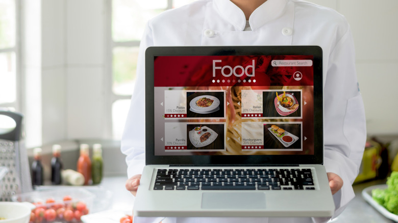 Chef holding a laptop with a restaurant website pulled up