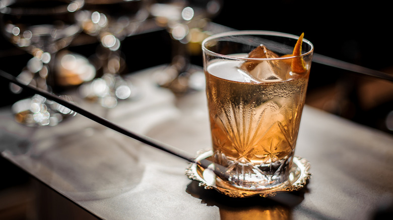An etched cocktail glass with a cold drink on a bar cart