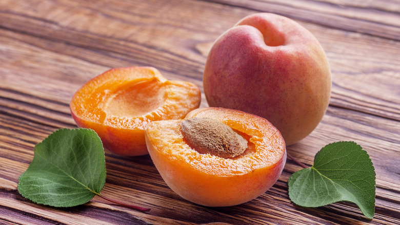 Sliced and whole apricot on wooden table