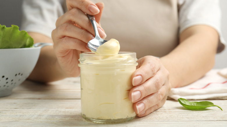 person holding jar of mayonnaise and spoon