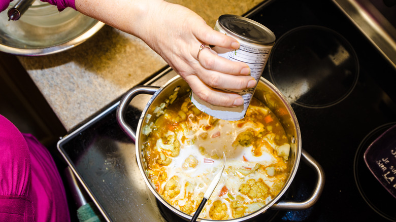 Pouring coconut milk into pot