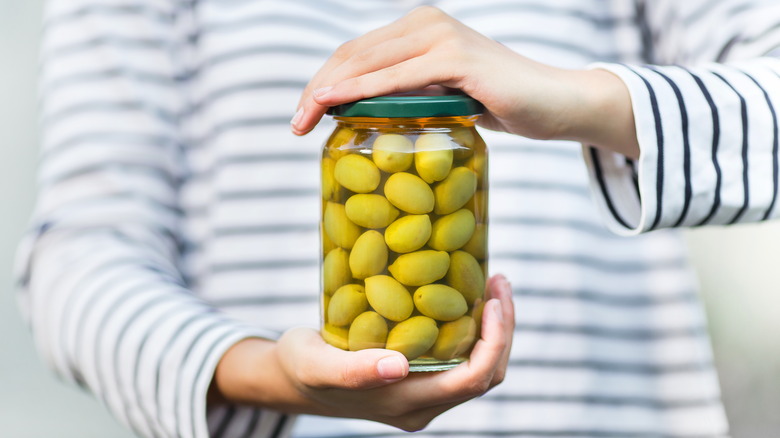 Hands holding jar of olives