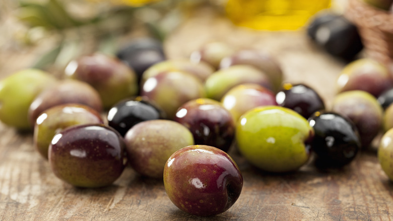 Various olives laid on wooden board