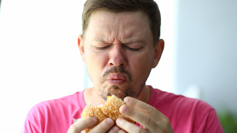 Person expressing disgust at burger