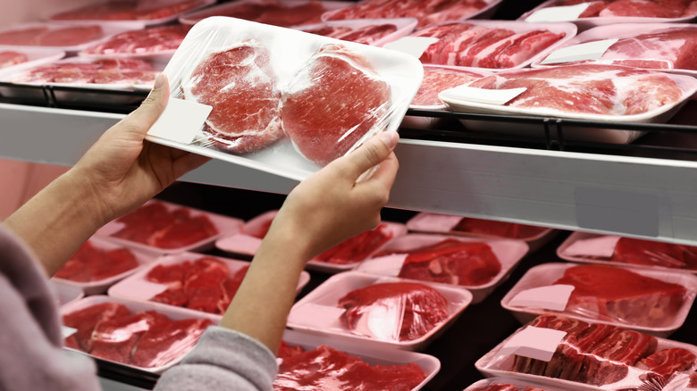 Person observing package of meat