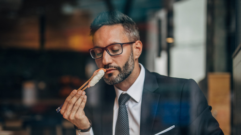 Man in restaurant smelling sushi