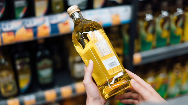 person looking at olive oil in grocery store