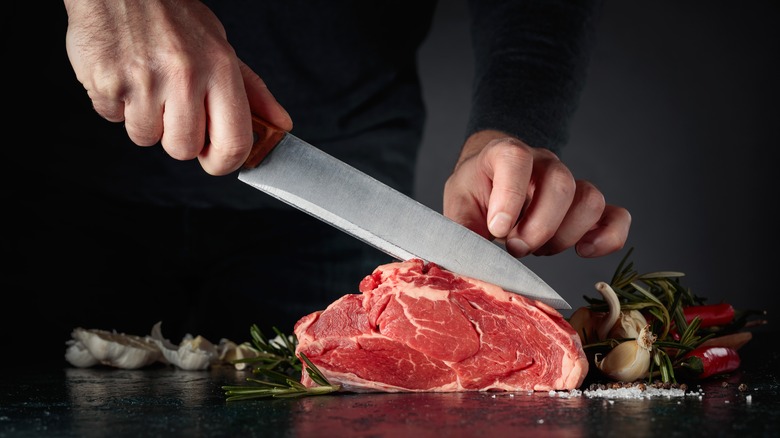hands slicing raw steak