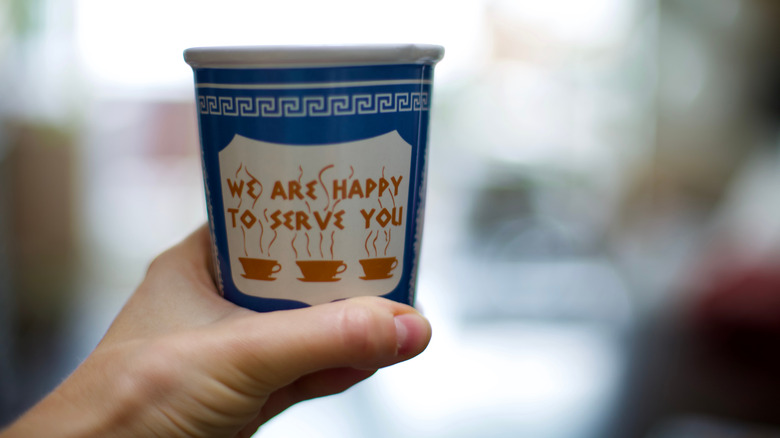 Hand holding Anthora coffee cup