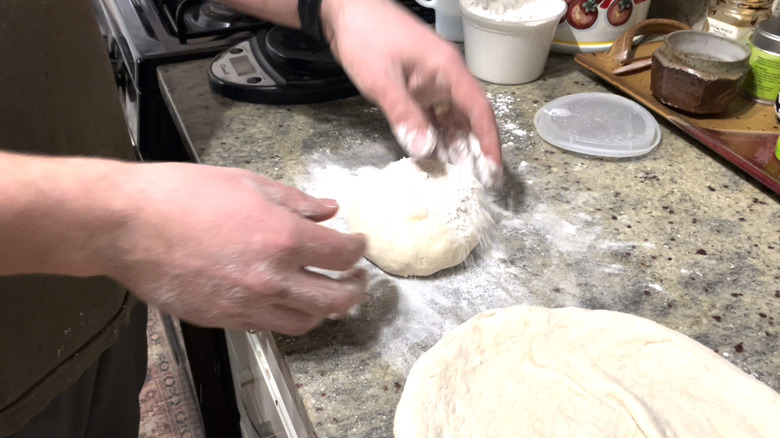 Dusting pizza dough with flour