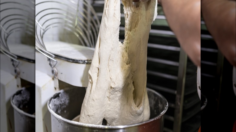 Person stretching wet pizza dough