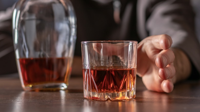 man reaching for bourbon glass