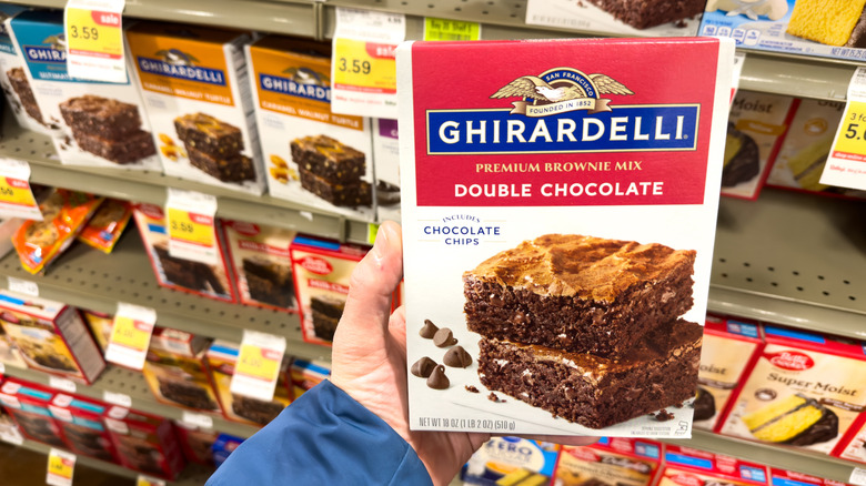 Person holding box of Ghiradelli brownie mix in grocery store aisle