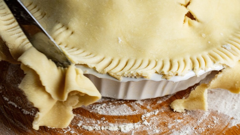 trimming excess crust off a pie