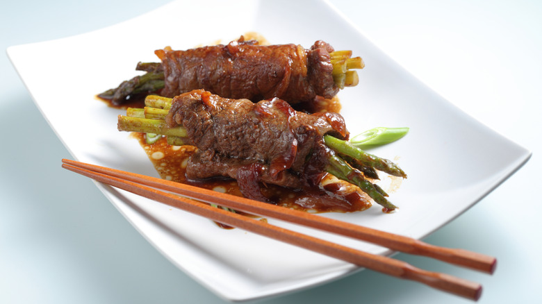 beef negimaki with asparagus on white plate