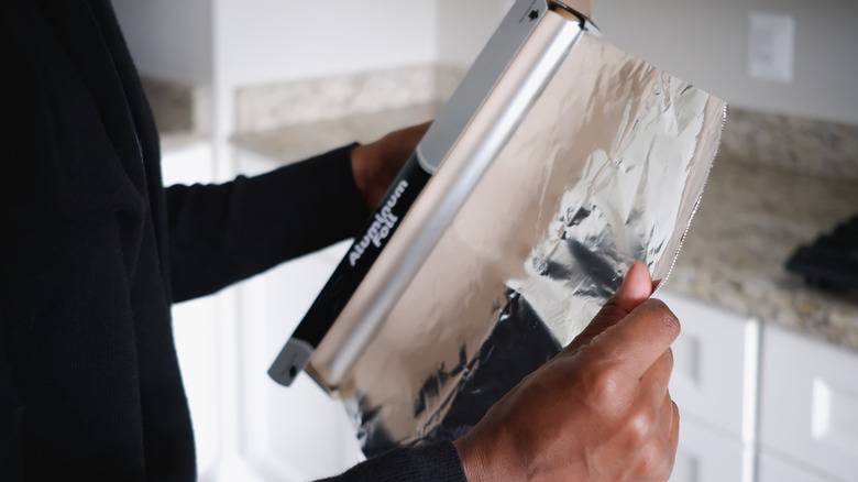 hands unwrapping aluminum foil