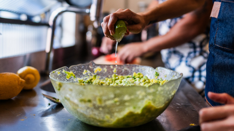 squeezing lemon into bowl of avocado