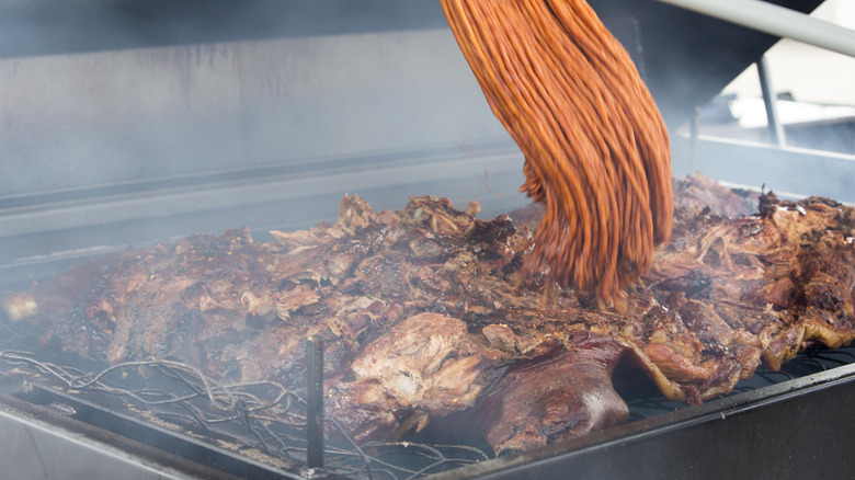 pitmaster using bbq mop on meat