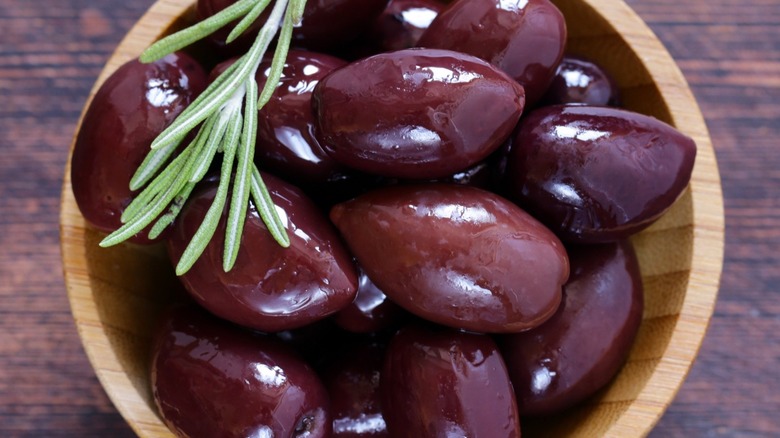 Top-down view of Kalamata olives in a wood bowl on a wood surface